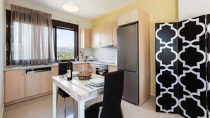 Una cocina moderna con armarios de madera, un refrigerador de acero inoxidable y un comedor con una mesa blanca y sillas negras.