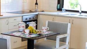 A kitchen with a dining table set for breakfast, including a plate of fruit, a cup, and a teapot. - Stunning one Bedroom Apartment in Loutra (Rethymno)
