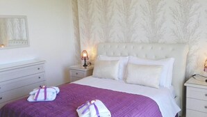 A neatly made bed with a purple bedspread and two towels, a white headboard, and a nightstand with a lamp. - Residence Maresol 1 Bedroom Apartment (Vieste)