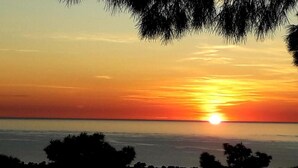 A sunset over a body of water with silhouettes of trees in the foreground. - Residence Maresol 1 Bedroom Apartment (Vieste)