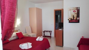 A hotel room with a bed, a desk, a chair, and a painting on the wall. - Residence Maresol Studio Apartment With Sea View (Vieste)