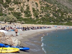A beach with kayaks, umbrellas, and people relaxing. - S West Crete Cottage (Kantanos-Selino)