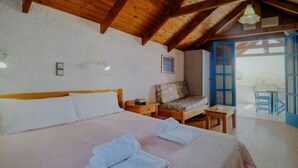 A bedroom with a wooden ceiling, a bed with pillows, a nightstand, a small table, and a chair. - Exclusive Cottages are in S West Crete in a Quiet Olive Grove Near the sea (Kantanos-Selino)