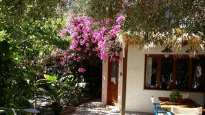 An outdoor patio with blue chairs, a table, and a building with a wooden door and window. - Exclusive Cottages are in S West Crete in a Quiet Olive Grove Near the sea (Kantanos-Selino)
