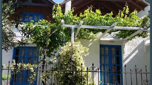 A building with two blue-framed windows, a white exterior, and a wooden roof. - Exclusive Cottages are in S West Crete in a Quiet Olive Grove Near the sea (Kantanos-Selino)