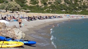 Ein Strand mit Kajaks, Sonnenschirmen und entspannenden Menschen.