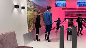 A bowling alley with a large mural, a purple couch, and a table with snacks and drinks. - Northseachalets Ameland (Buren)