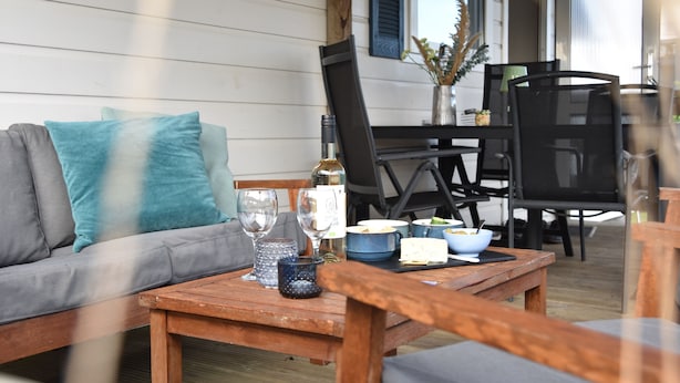 A wooden table with a bowl, wine glasses, and a candle. - Northseachalets Ameland (Buren)