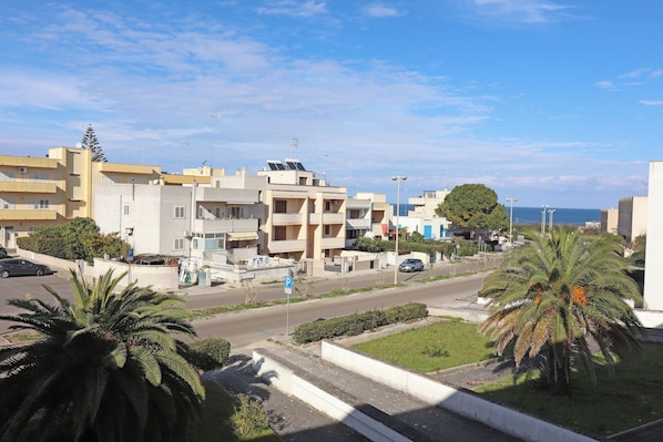 A residential area with modern buildings, a palm tree, and a clear sky.