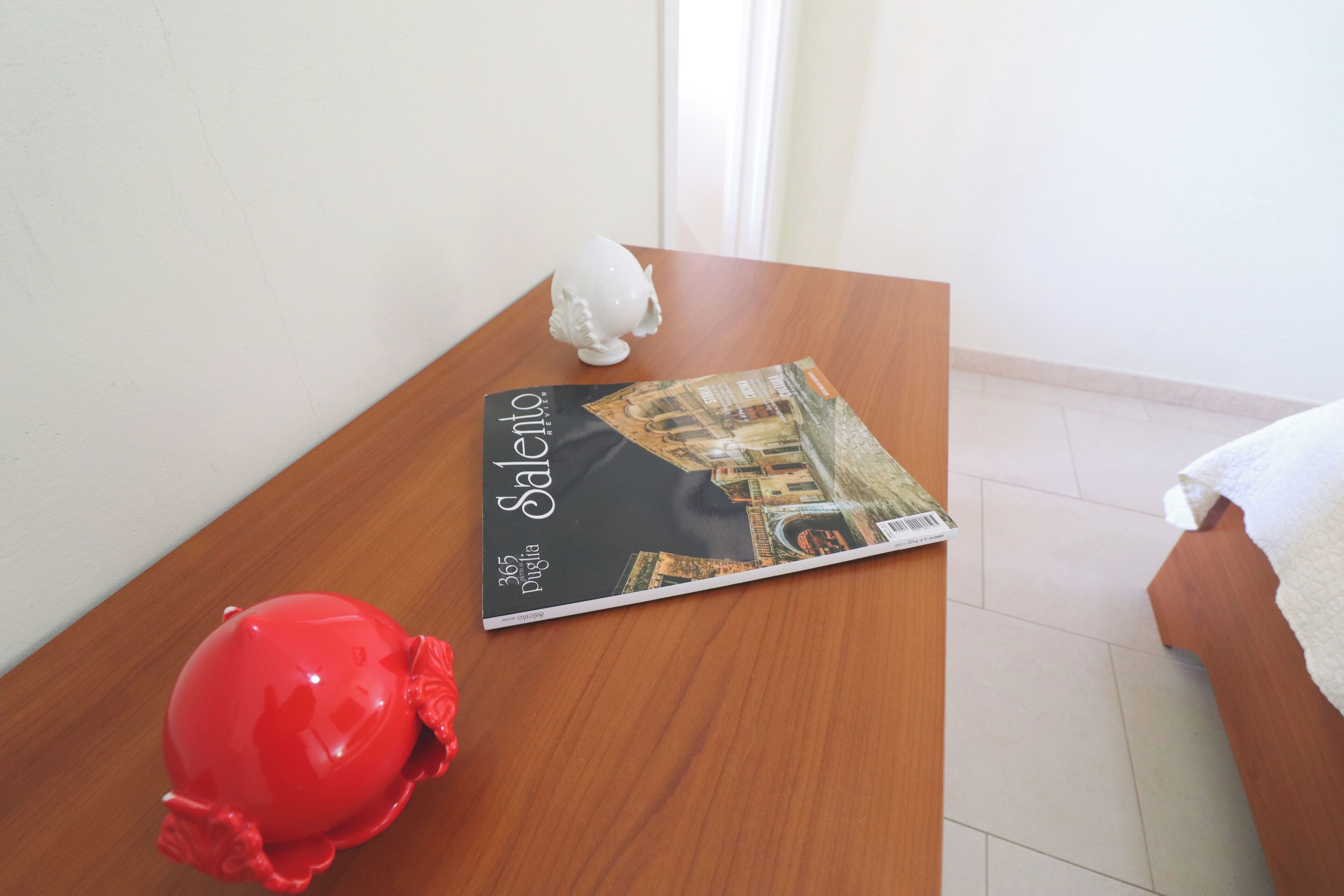Una mesa de madera con un libro titulado 'Salento' y un objeto decorativo blanco.