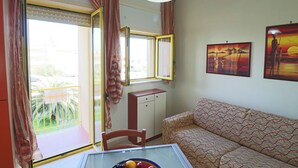 A room with a sofa, a dining table with fruit, a window with curtains, a cabinet, and wall art. - Casa Lucia Sea Breeze, Comfort and Relaxation by the Otranto Lighthouse (Otranto)