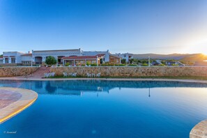 Un resort con piscina, mobiliario exterior y vistas a las montañas.