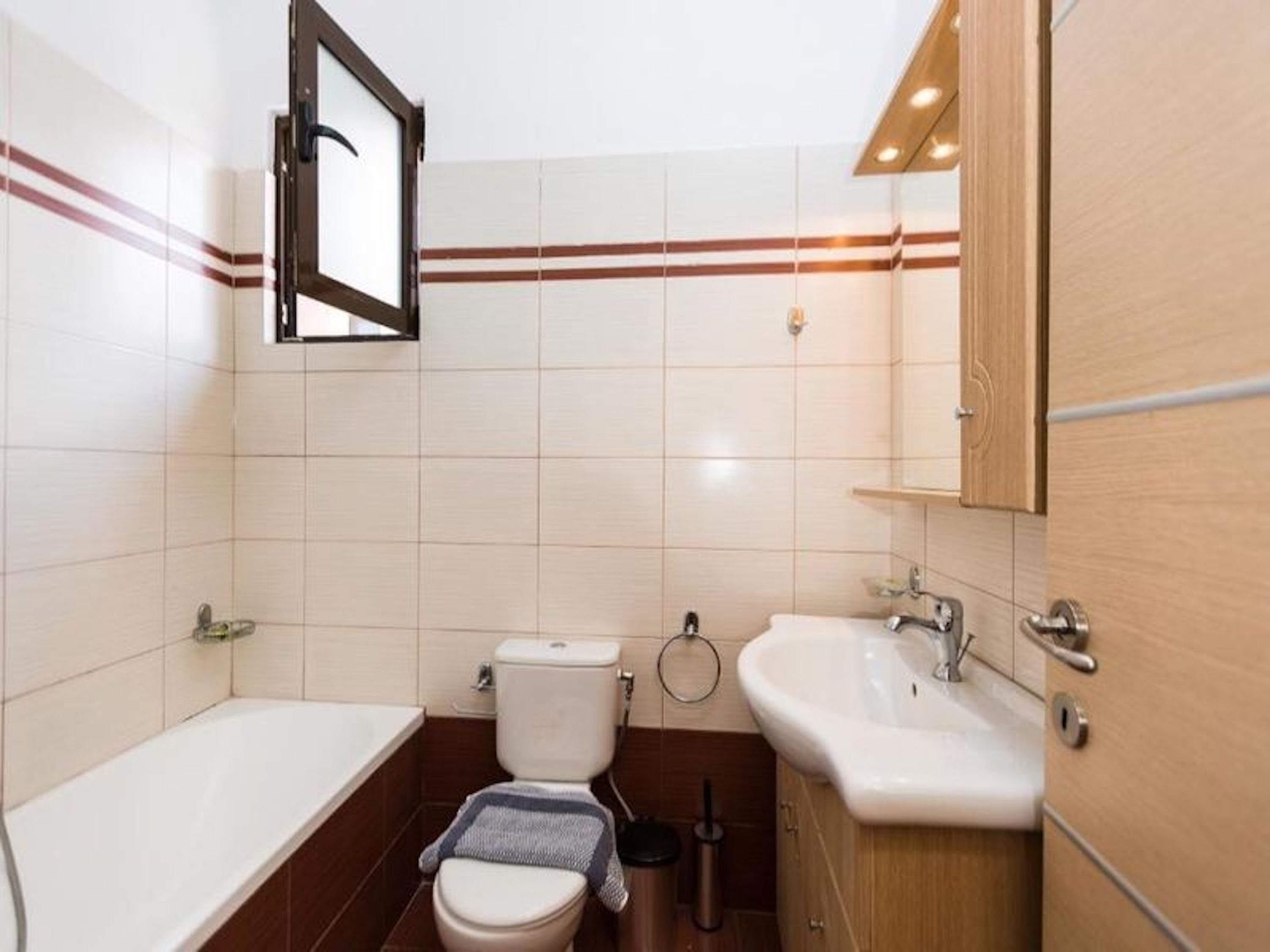 A bathroom with a bathtub, toilet, sink, and mirror.