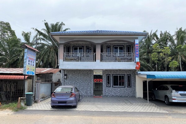 Een motel met twee verdiepingen, een balkon op de bovenste verdieping, een overdekte parkeerplaats en een bord met de naam 'OYO'.