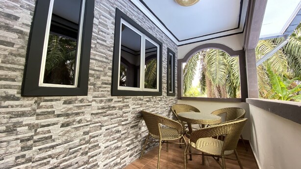 A balcony with stone-patterned walls, large windows, wicker chairs, and a table. - Hotel O Bayu Sintok Motel (Changlun)