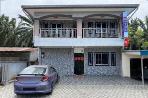 Een gebouw met twee verdiepingen, een stenen gevel en een balkon op de bovenverdieping, met een bord waarop 'MOTEL OYO' staat.
