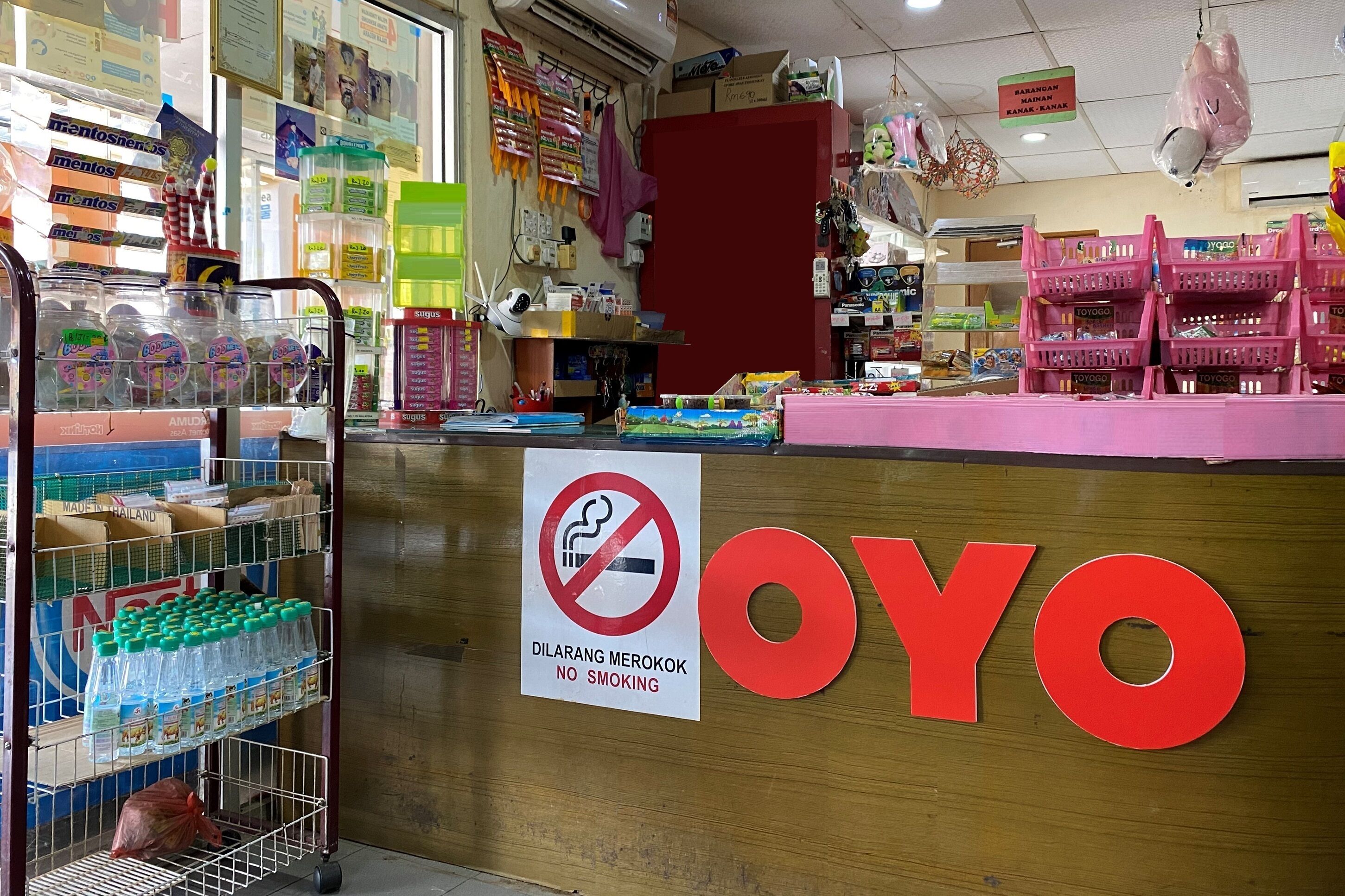 A store interior with shelves stocked with snacks, a 'No Smoking' sign, and the 'OYO' brand prominently displayed.