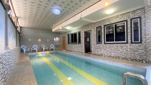 An indoor swimming pool with a stone wall and windows. - Hotel O Bayu Sintok Motel (Changlun)