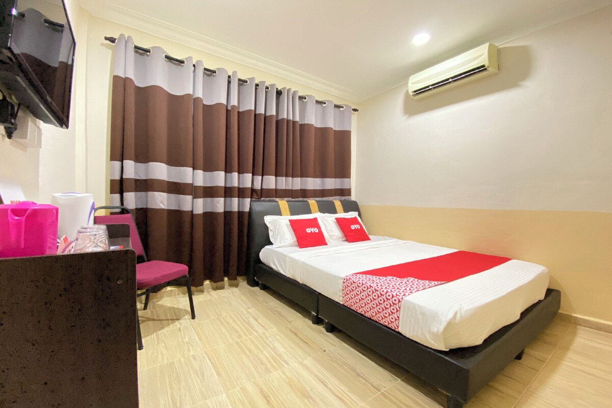 Une chambre d’hôtel équipée d’un lit, d’un bureau, d’une chaise, d’un miroir, de rideaux et d’un appareil de climatisation.