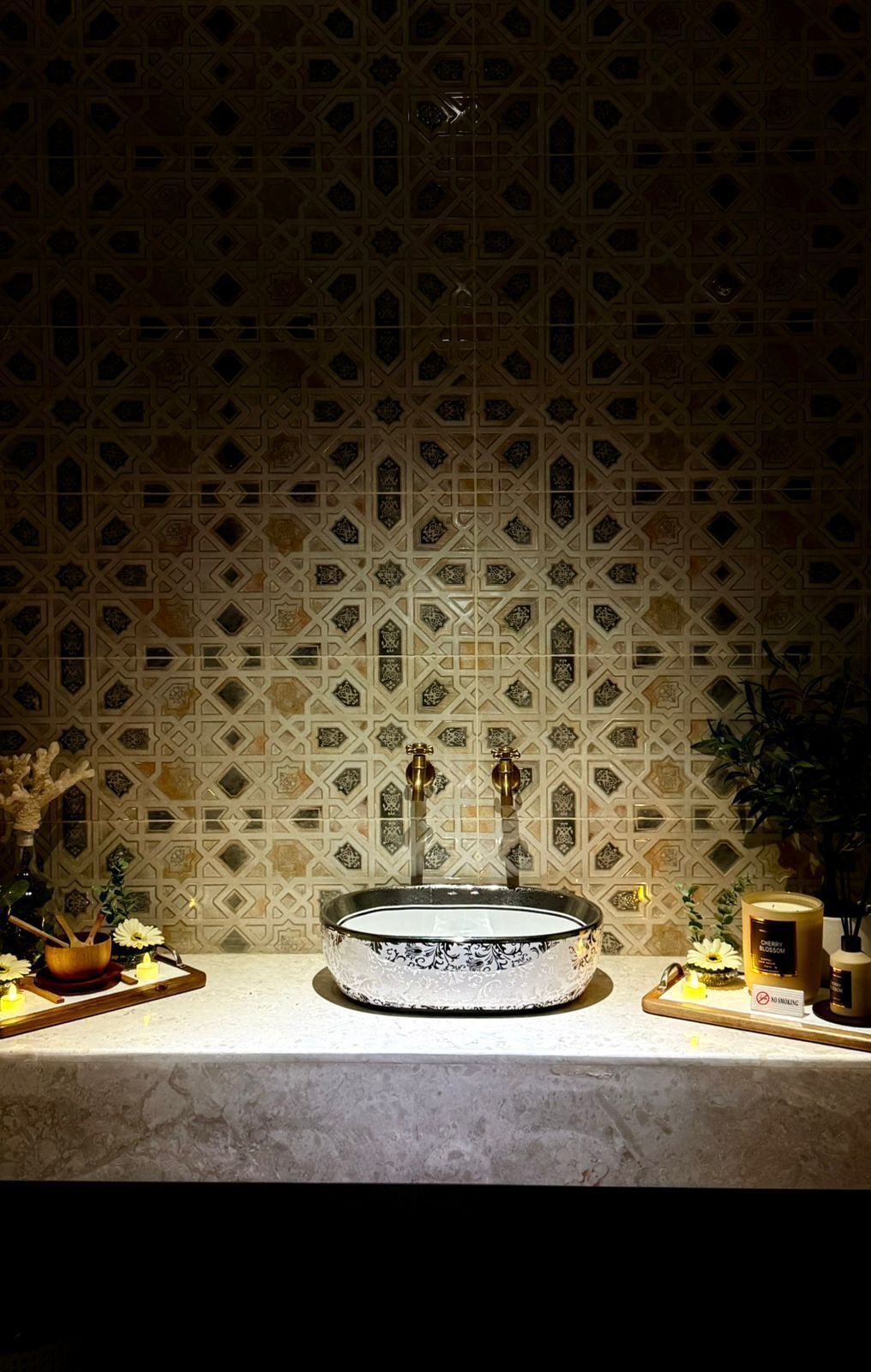 A bathroom with a patterned tile backsplash, a round sink with a decorative basin, and a small plant on the counter.