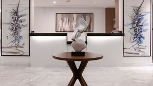 A reception area with a modern design, featuring abstract art on the walls, a central sculpture on a round table, and a sleek reception desk. - Iris Boutique Taif Heart (Taif)