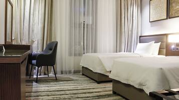 Una habitación de hotel con cama, escritorio, silla y zona de ducha.