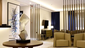 A modern living room with a round table, beige sofas, a TV, and a decorative abstract painting. - Iris Boutique Taif Heart (Taif)