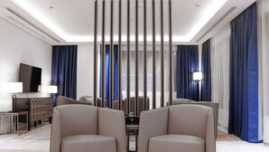 A modern hotel room with a seating area featuring two armchairs, a sofa, and a TV on a stand. - Iris Boutique Taif Heart (Taif)
