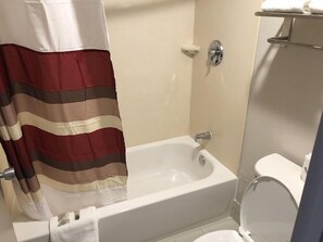 A bathroom with a bathtub, toilet, and a shower curtain.