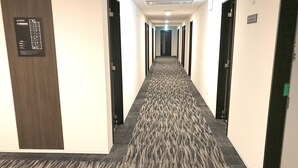 A hotel hallway with carpeted floors, doors on both sides, and a sign on the left wall. - HOTEL LiVEMAX Takamatsu Eki Mae (Takamatsu)