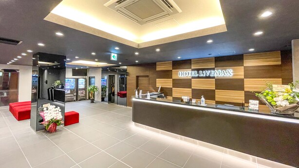 A hotel reception area with a modern design, featuring a checkered wall pattern, a reception desk, and a ceiling with recessed lighting. - HOTEL LiVEMAX Takamatsu Eki Mae (Takamatsu)