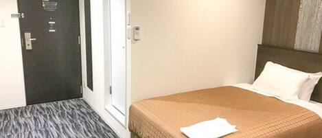 Quarto de hotel com uma cama, uma porta e um aparelho de ar condicionado.