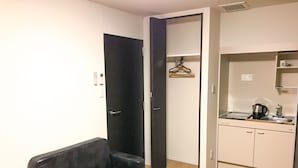 A compact living space with a sofa, a wooden table, a kitchenette, and a wardrobe. - HOTEL LiVEMAX Takamatsu Eki Mae (Takamatsu)