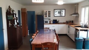 A spacious kitchen with a long wooden table, cabinets, and a microwave.