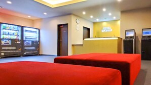 Ein Hotel-Empfangsbereich mit Rezeption, einer Uhr und Verkaufsautomaten.