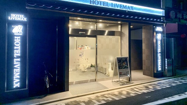 Ein Hotel Eingang mit modernem Design, mit einem gut sichtbaren Schild für HOTEL LIVEMAX und einer einladenden Eingangstür.