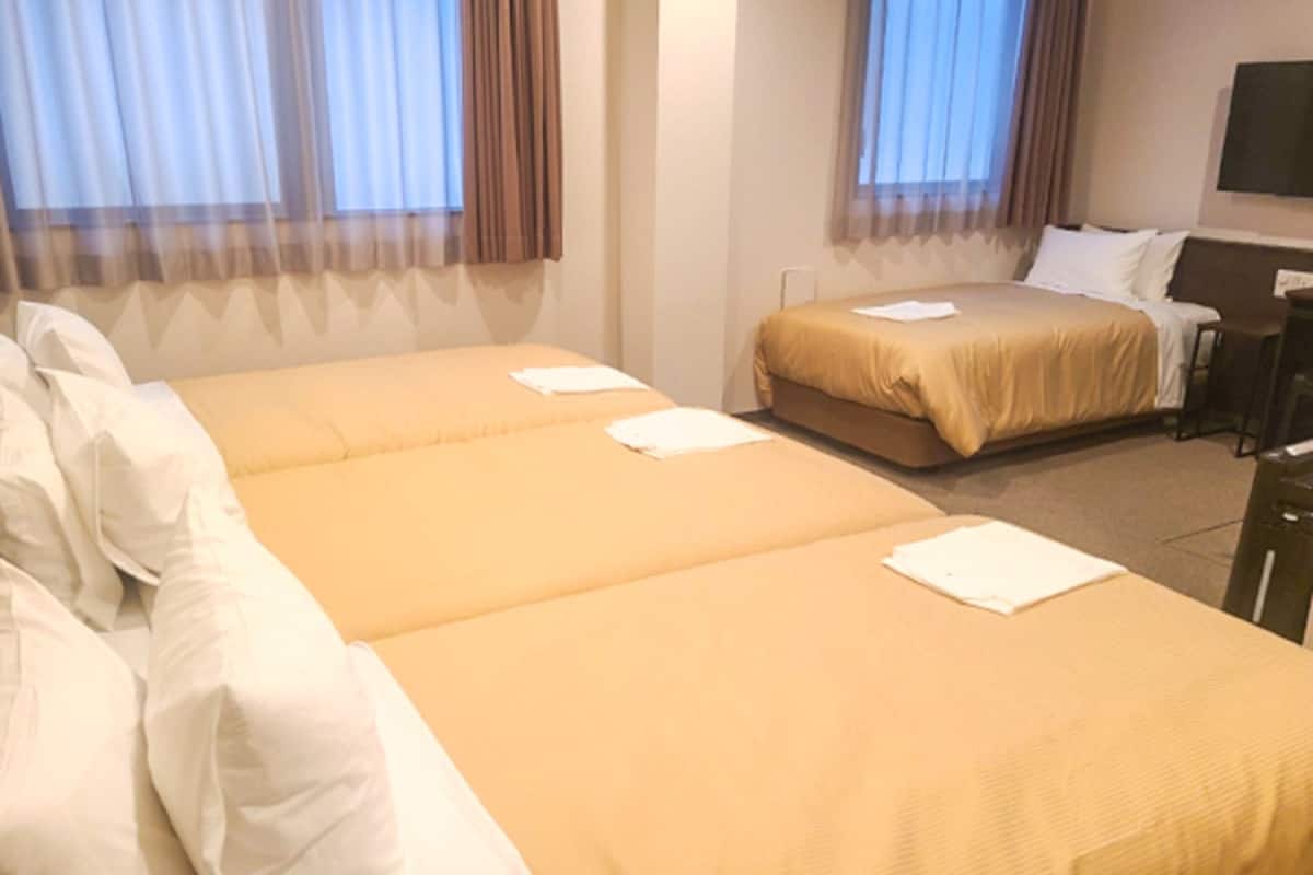 A hotel room with two single beds, a desk, and a chair.