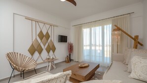 Een moderne woonkamer met een bank, een houten salontafel, een decoratieve wandversiering en een plafondventilator.
