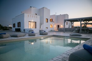 Una villa moderna con piscina, area salotto esterna e portico coperto.