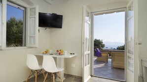 Una zona de menjador petita amb taula, dues cadires, televisió i vista a l'exterior.