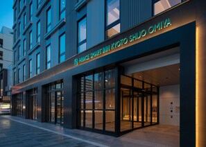 Ein moderner Hotelzugang mit Glasfassade und beleuchteter Beschilderung.