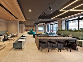 A modern office space with a long counter, seating area, and large windows.