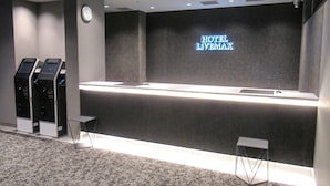 Un espace d’accueil d’hôtel doté d’un mur d’affichage numérique, d’un comptoir d’accueil et de bornes en libre-service.