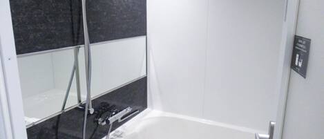 A modern bathroom with a bathtub, a shower, and a hand shower.