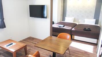 A hotel room with a bed, a TV, a desk, and an orange chair.