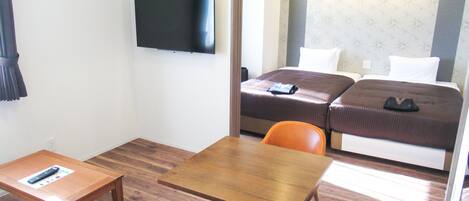 A hotel room with a bed, a TV, a desk, and an orange chair.
