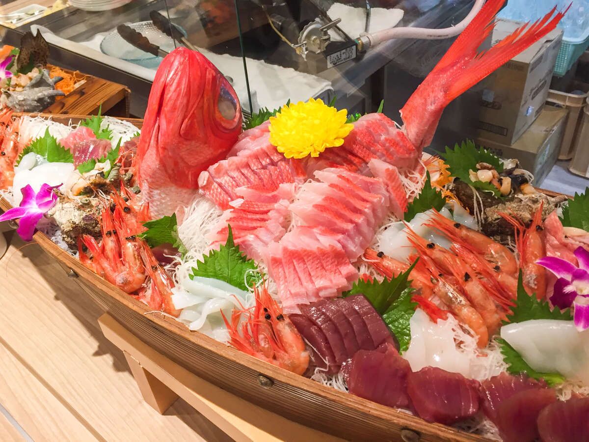 Eine Fischplatte mit verschiedenen Fischsorten, Garnelen und Beilagen.