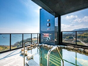 Une piscine intérieure moderne offrant une vue dégagée sur un paysage montagneux et un plan d’eau.