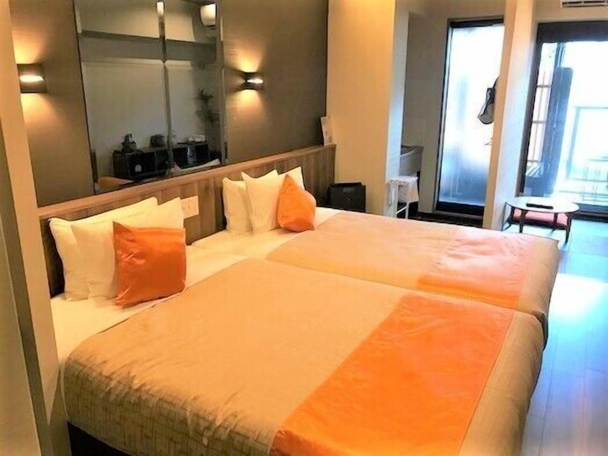 Ein Hotelzimmer mit zwei Betten, einem großen Spiegel und Blick nach draußen.
