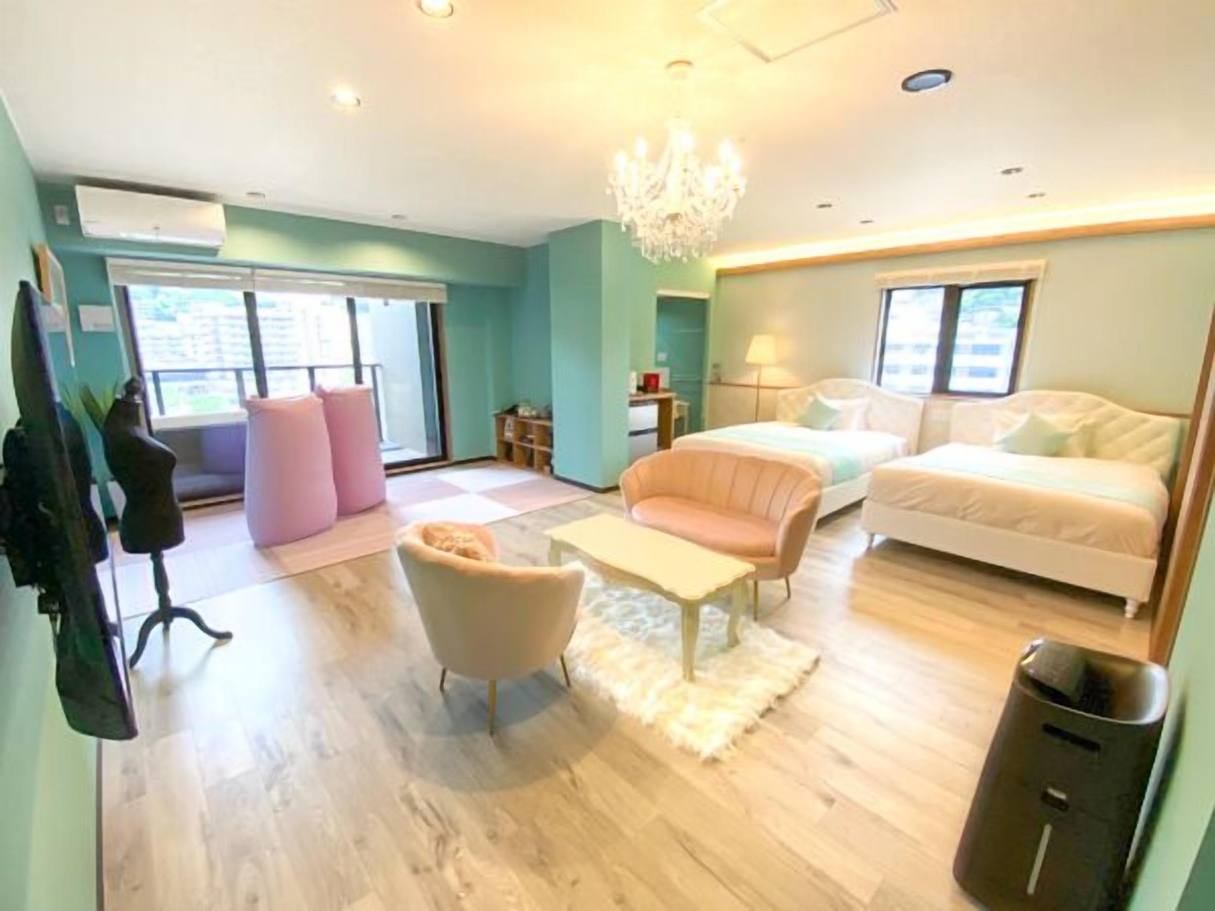 Ein modernes Hotelzimmer mit einem Bett, einem Schlafsofa, einem Sessel, einem kleinen Tisch und einem Mülleimer.
